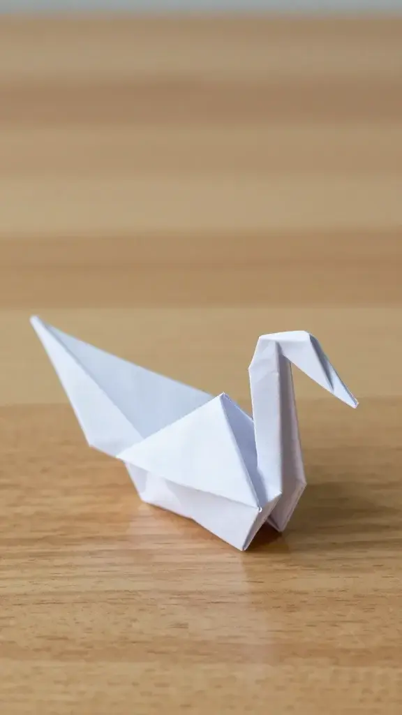 Single completed origami swan on wooden table