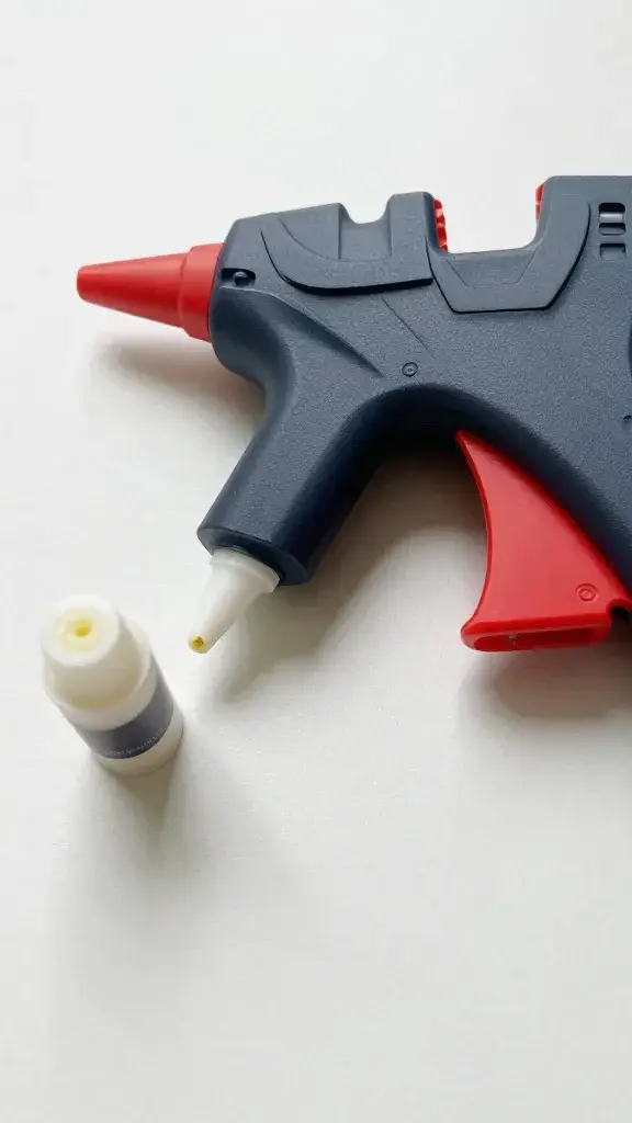 Hot glue gun with glue stick on crafting surface