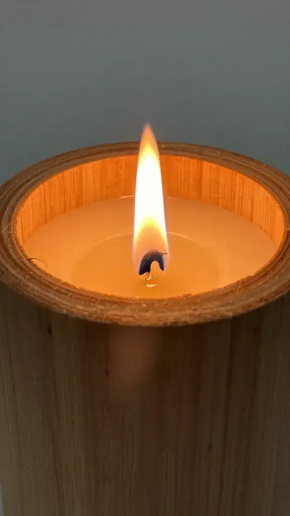 Closeup of burning wood wick candle with visible flame