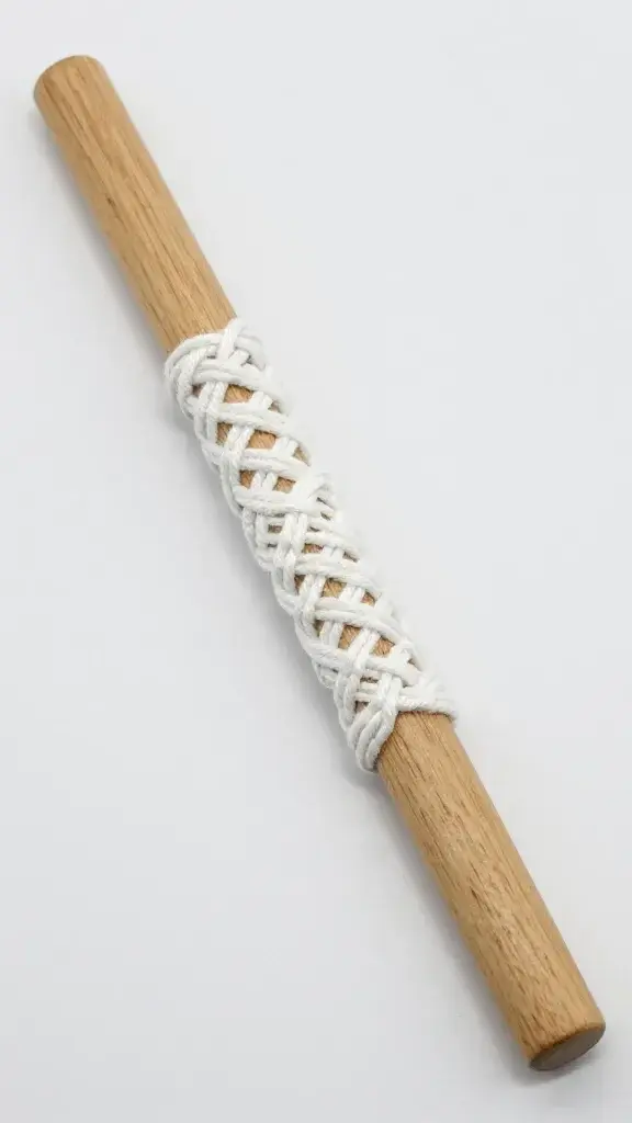 Wooden dowel rod with white macrame knots attached
