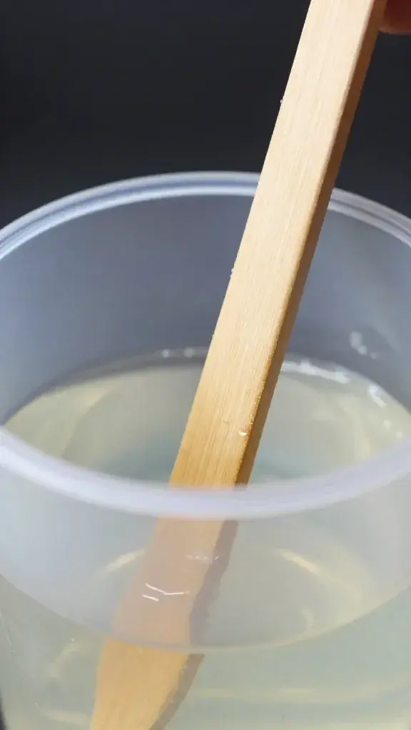 Wooden mixing stick stirring clear resin in cup